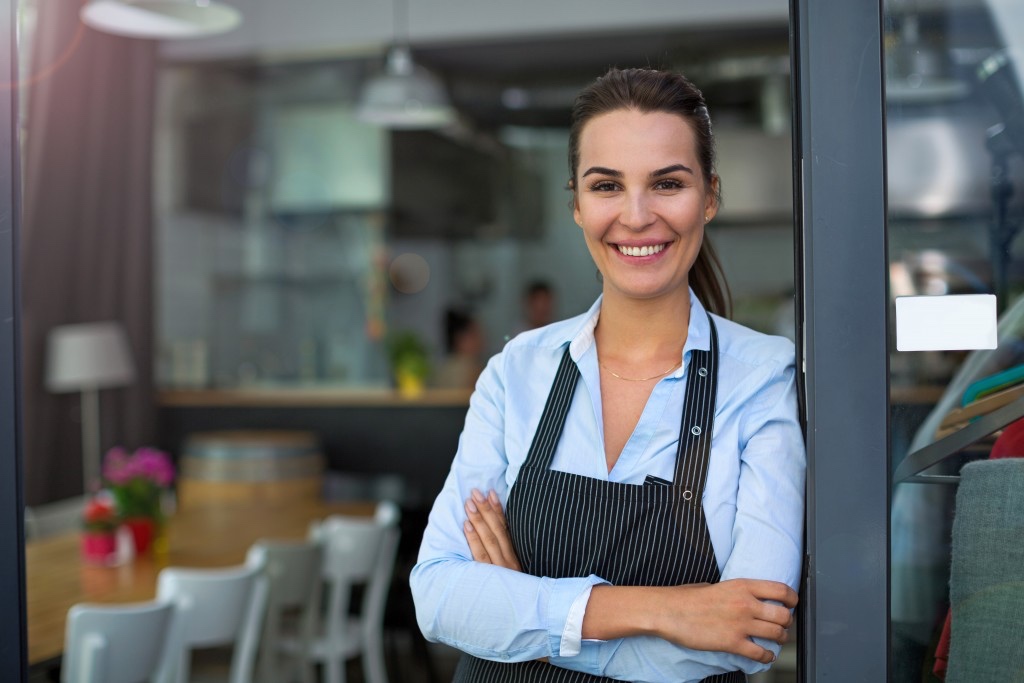 Confident small business owner standing in the doorway of her shop — the kind of brand a phrase trademark protects
